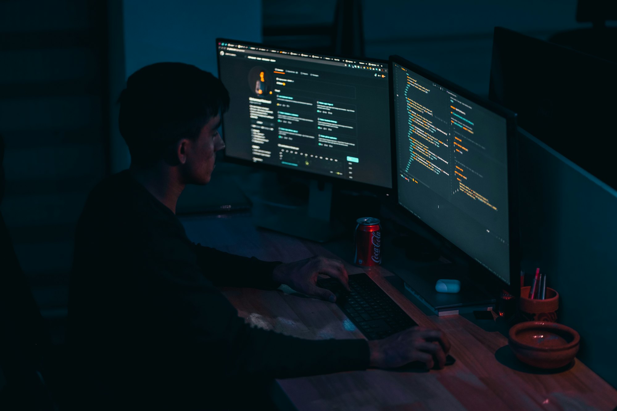 An analyst working across several monitors showing code and data