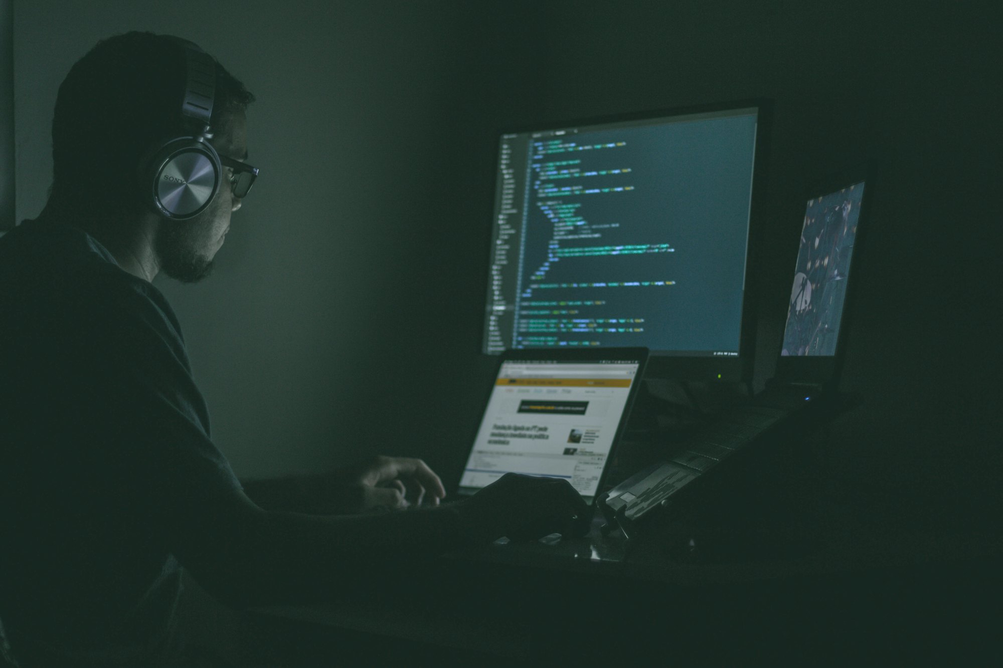 A specialist with headphones working at a computer in a dim office